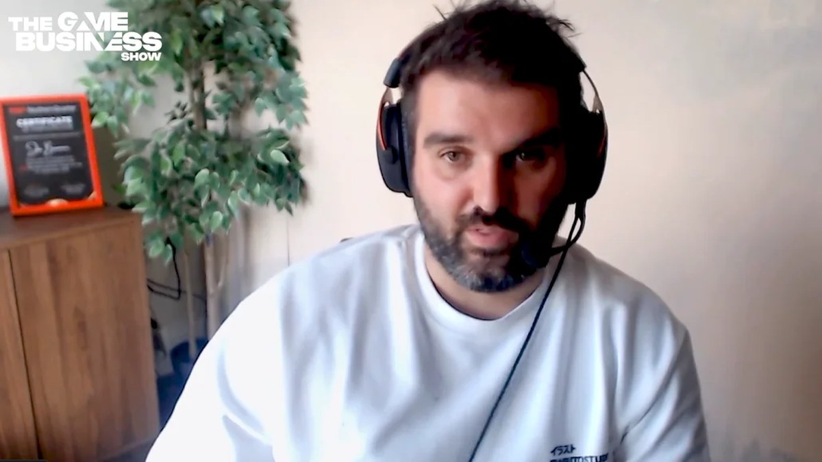 Bulkhead CEO Joe Brammer in a white t-shirt and set of headphones, appearing on The Game Business podcast.
