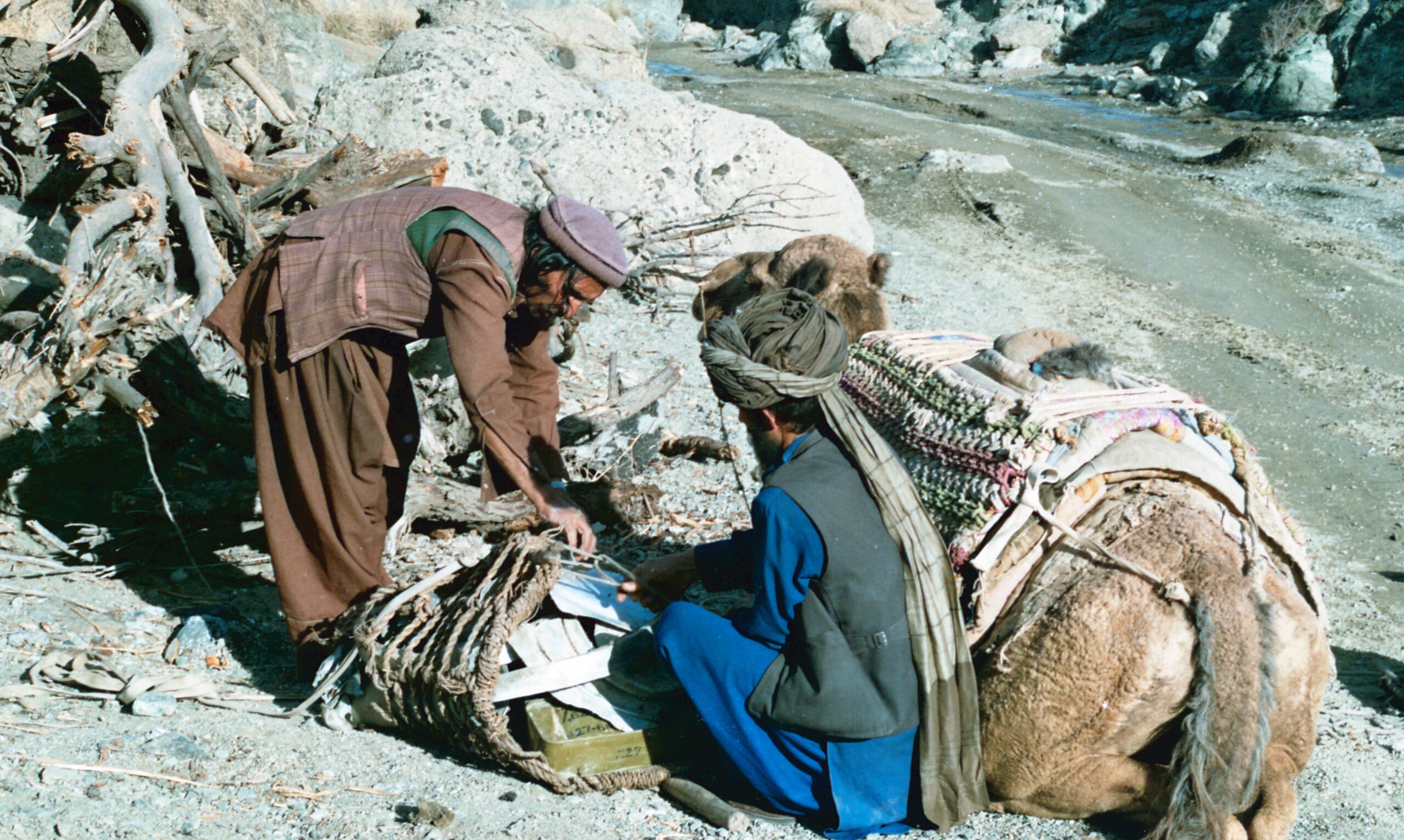 Two Muj tying parts of used ammunition in a net. — 1990-02-01T00:00:00Z Dönemi Askeri Tarih Belgesi