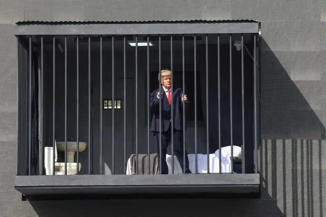 An Iranian actor in a Trump mask stands behind bars in a mock prison cell billboard